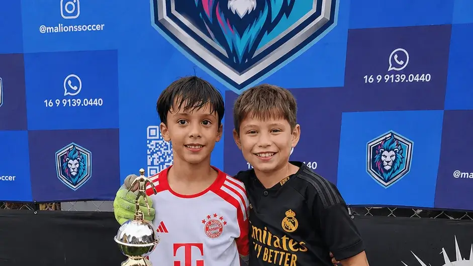 Duas crianças com medalhas diante do painel da Lions
