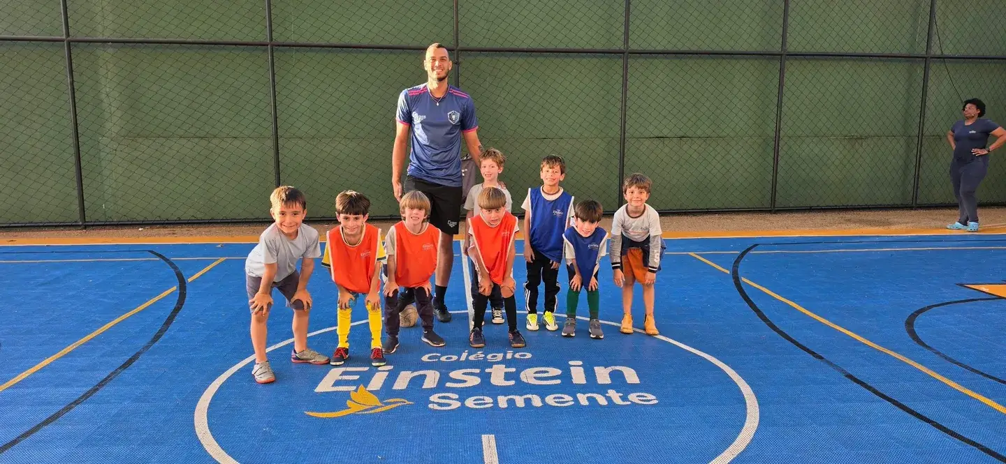 Turma de crianças reunida em uma quadra de esportes